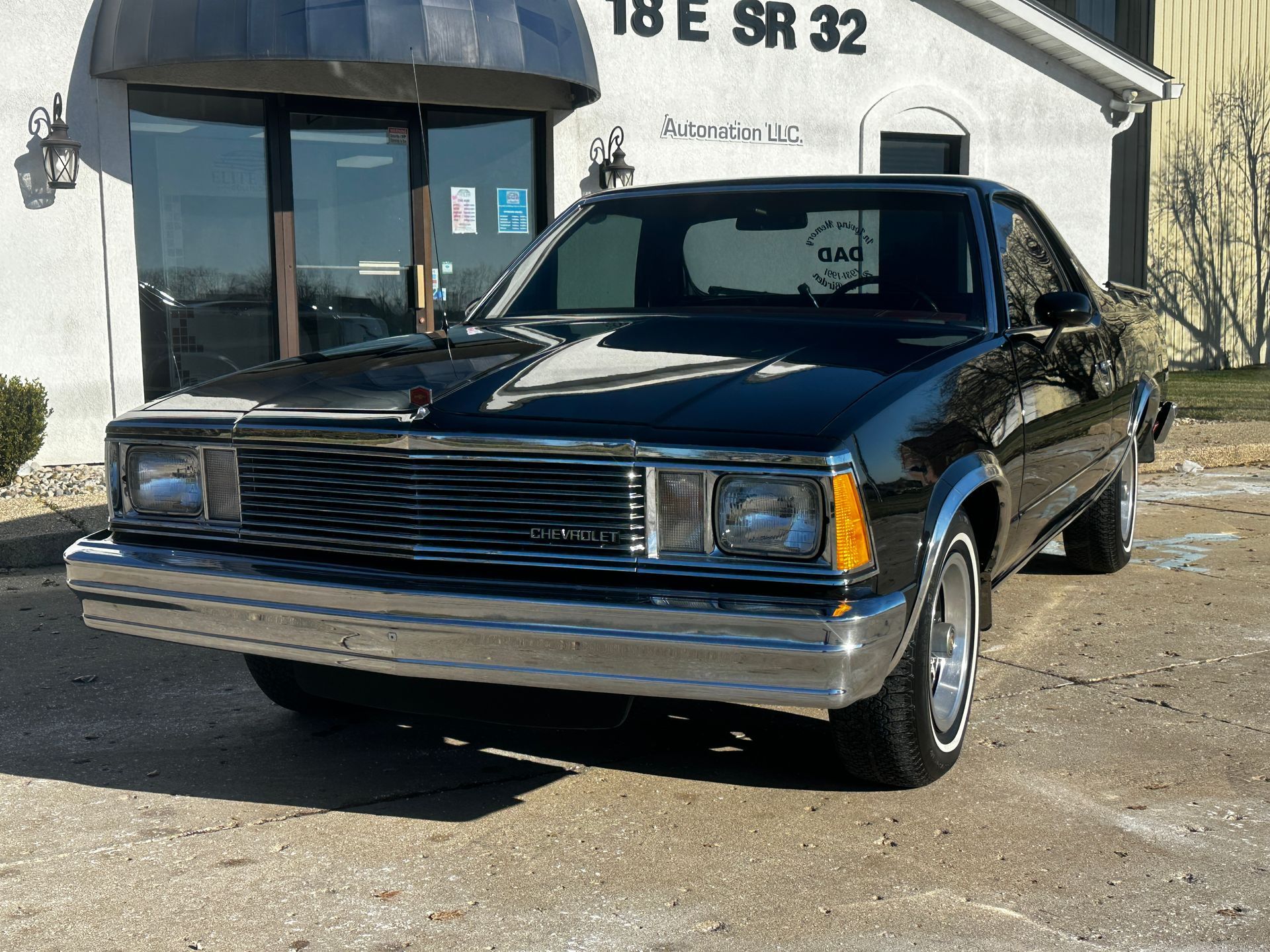 Black Chevrolet Malibu parked in front of a white building with SR 32 sign.