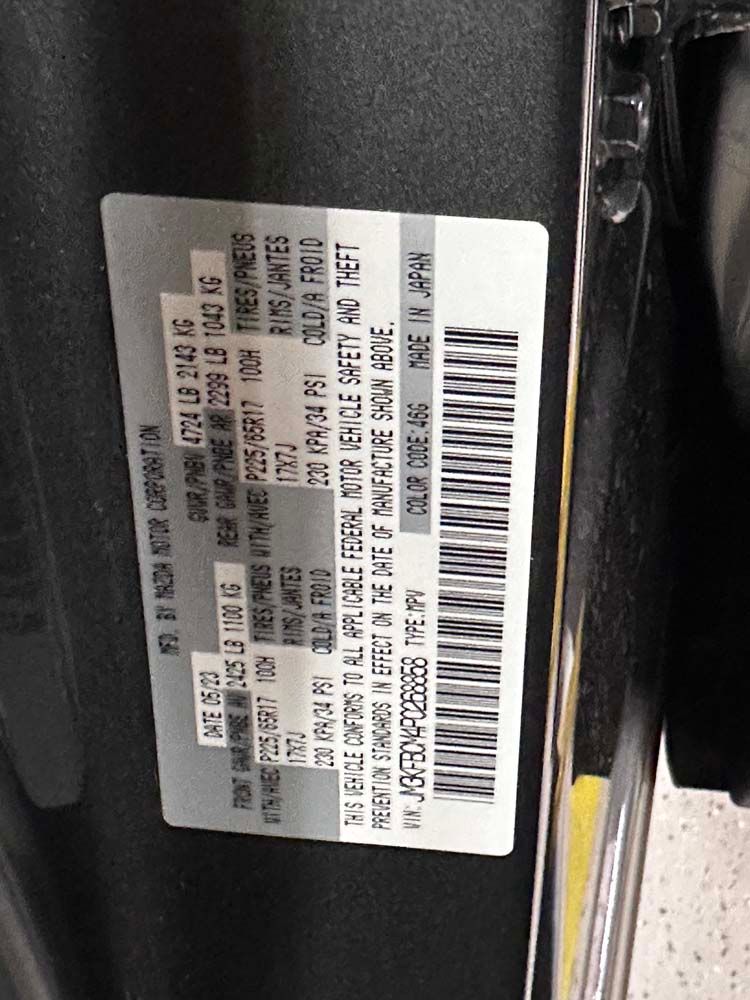 A gray car with a sticker on the side that says ' mazda ' on it