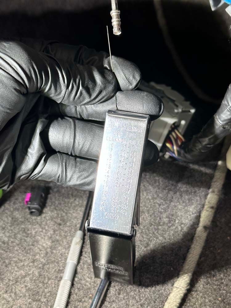 A person wearing black gloves is holding a metal object in their hand.