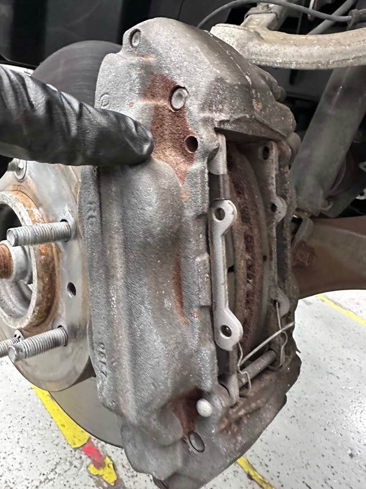 A close up of a person holding a brake caliper on a car.