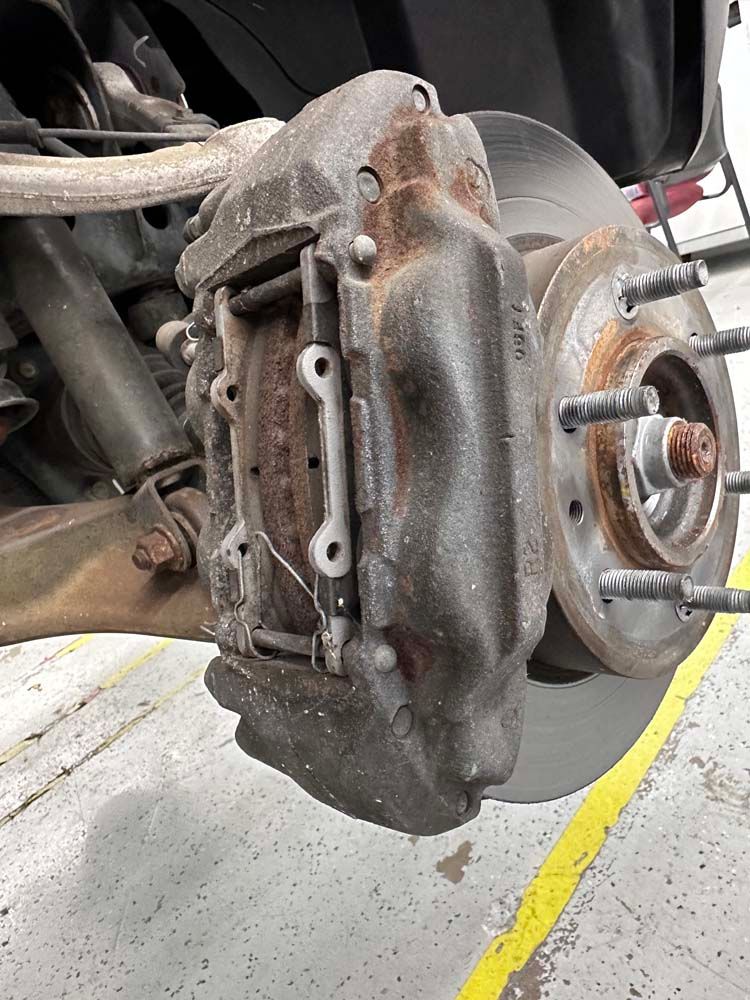 A close up of a brake caliper on a car in a garage.