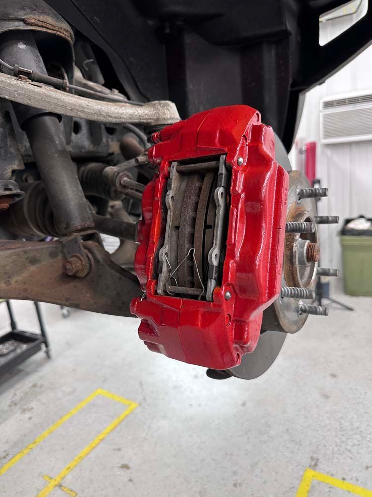 A close up of a red brake caliper on a car.