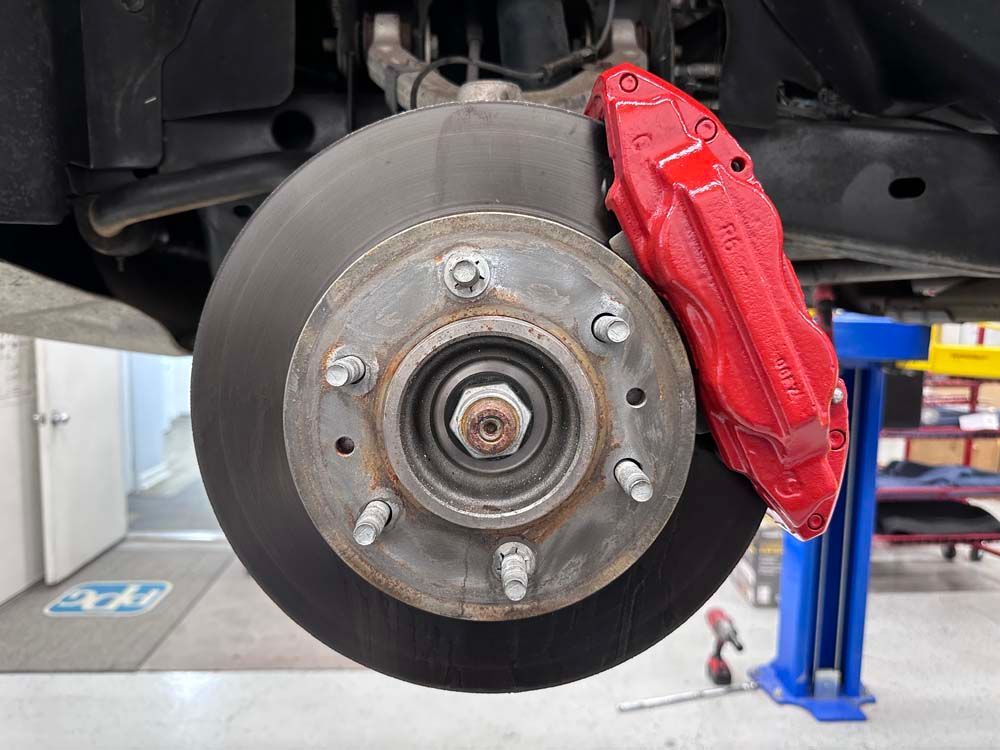 A car with a red brake caliper is sitting on a lift.