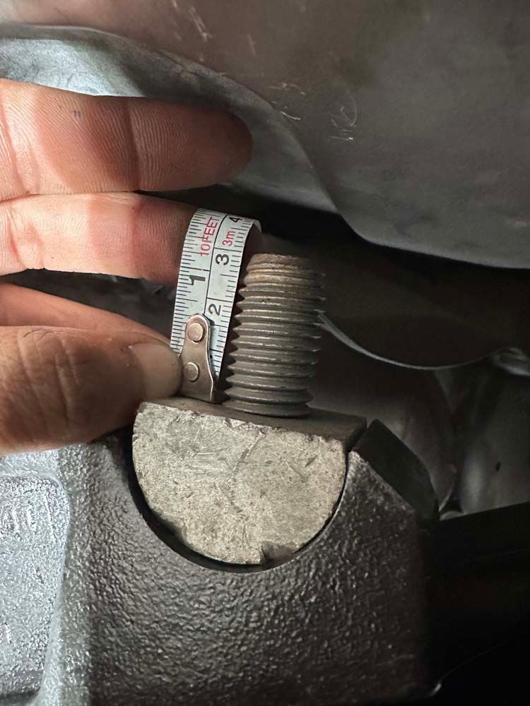 A person is measuring a metal object with a tape measure.