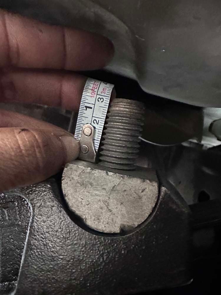 A person is measuring a bolt with a tape measure.