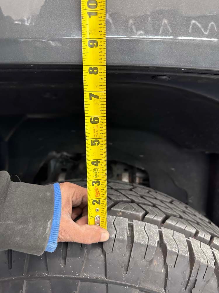 A person is measuring the height of a tire with a tape measure.
