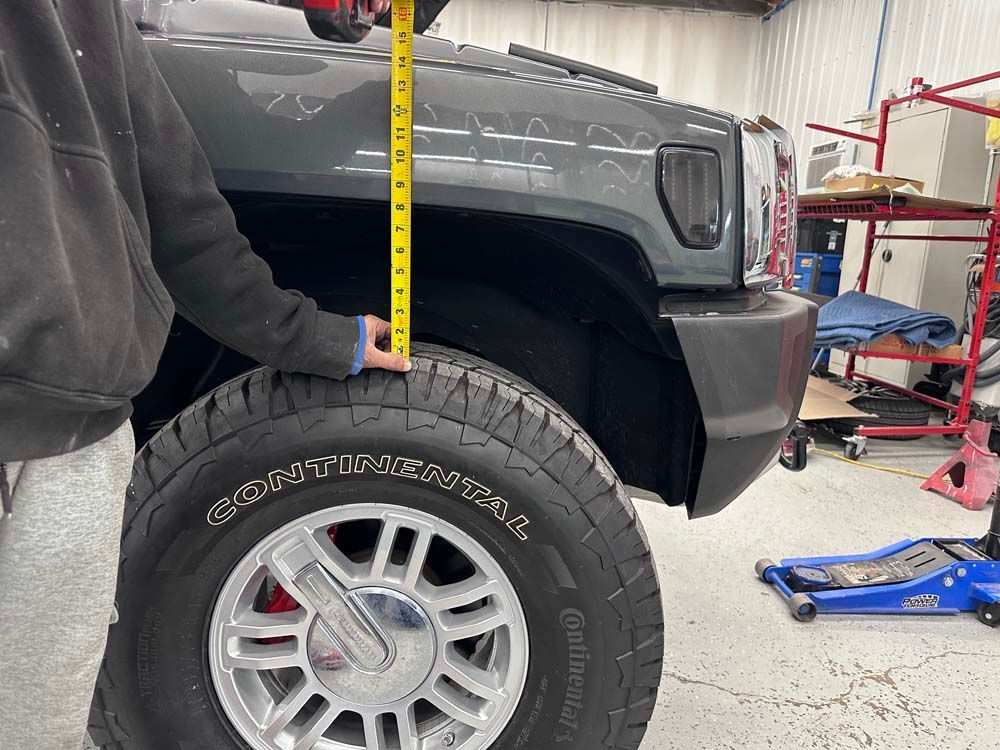A person is measuring the height of a truck with a tape measure.