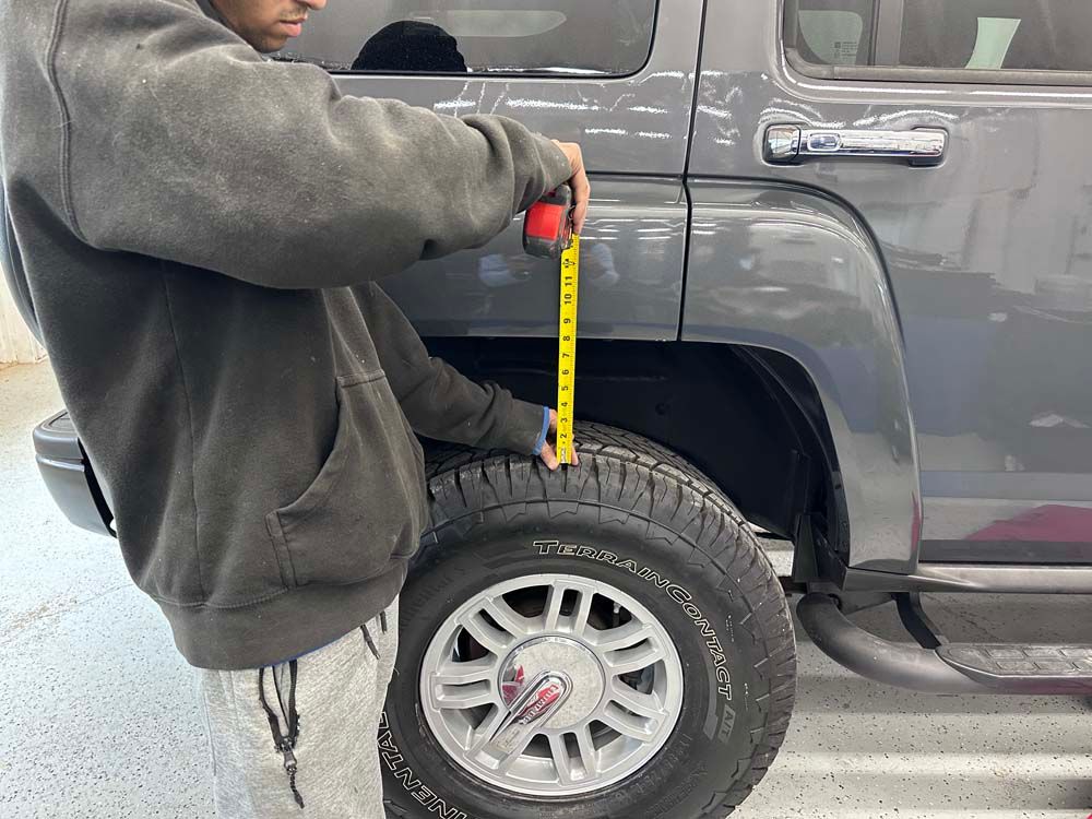 A man is measuring the height of a truck with a tape measure.