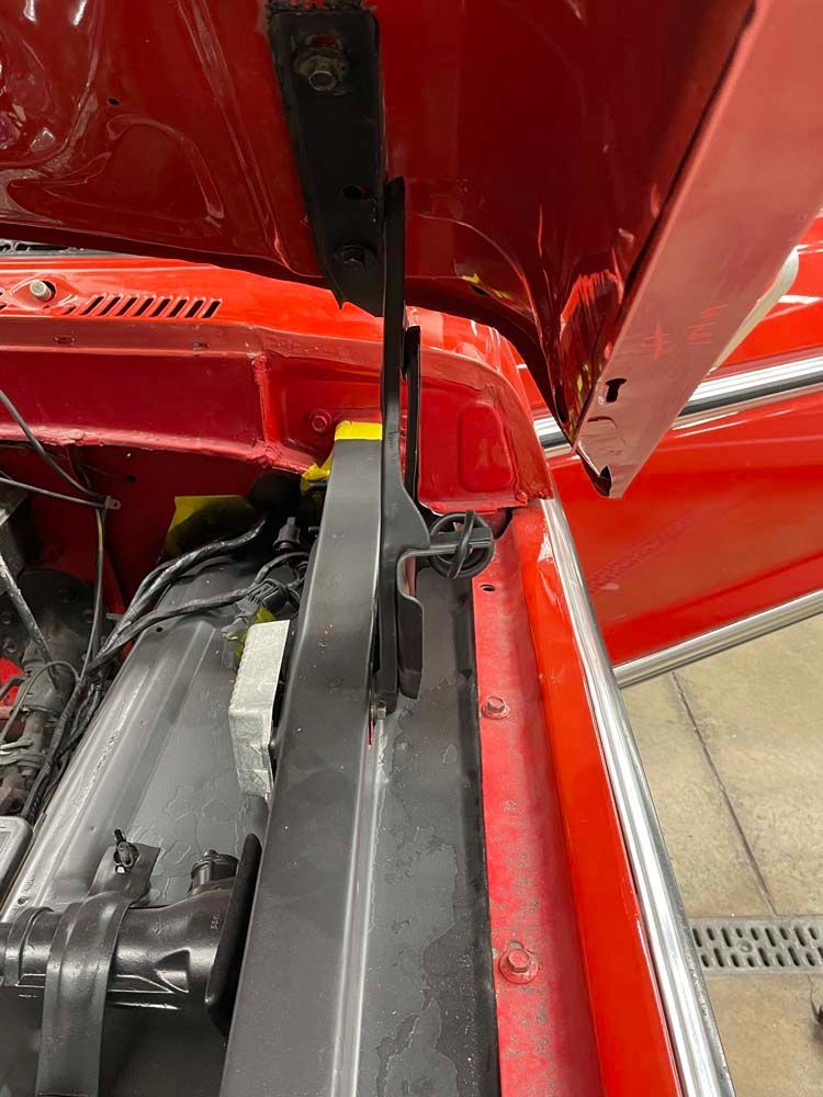 The hood of a red car is open and the radiator is visible.