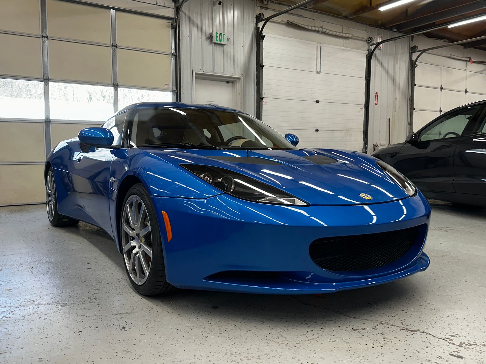 Blue Lotus Evora sports car parked inside a garage.