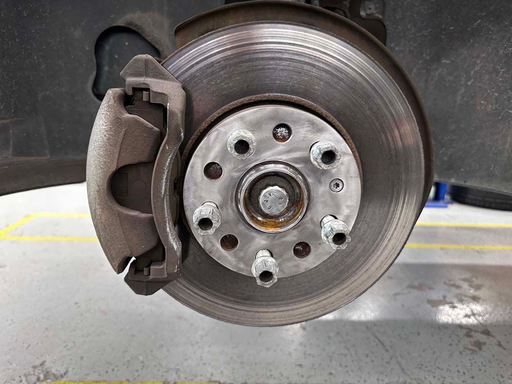 A close up of a brake disc on a car in a garage.