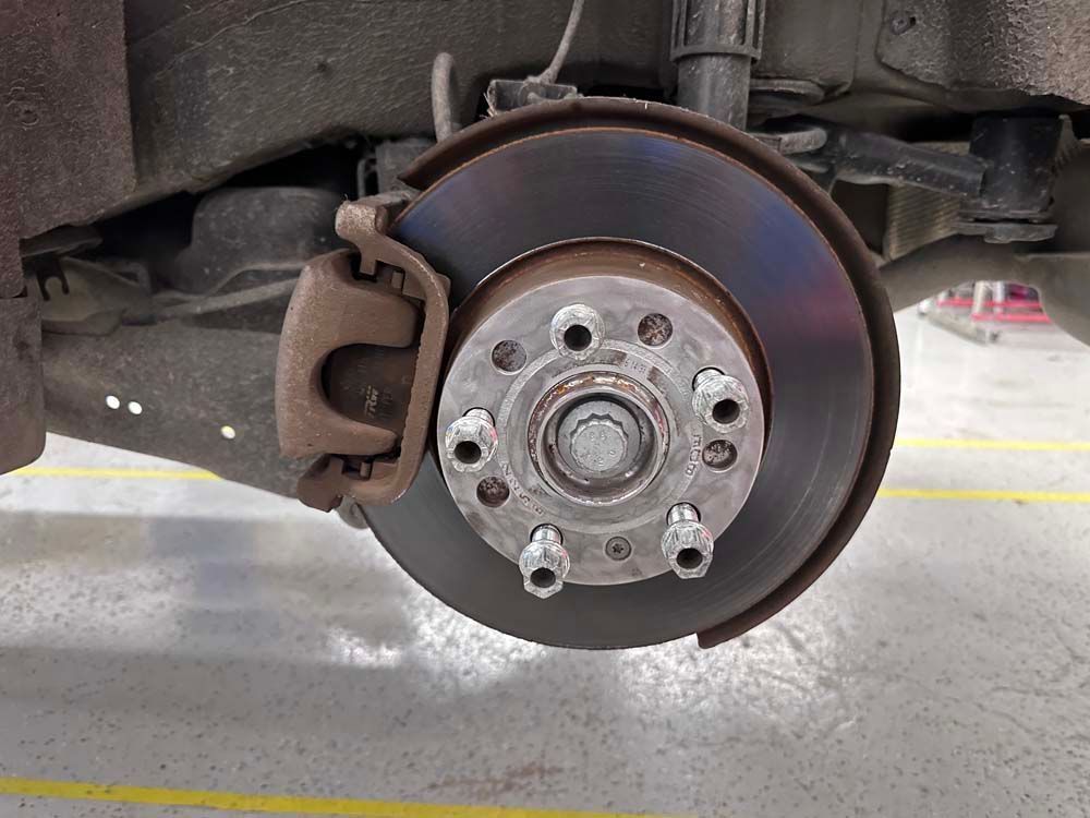 A close up of a brake disc on a car in a garage.