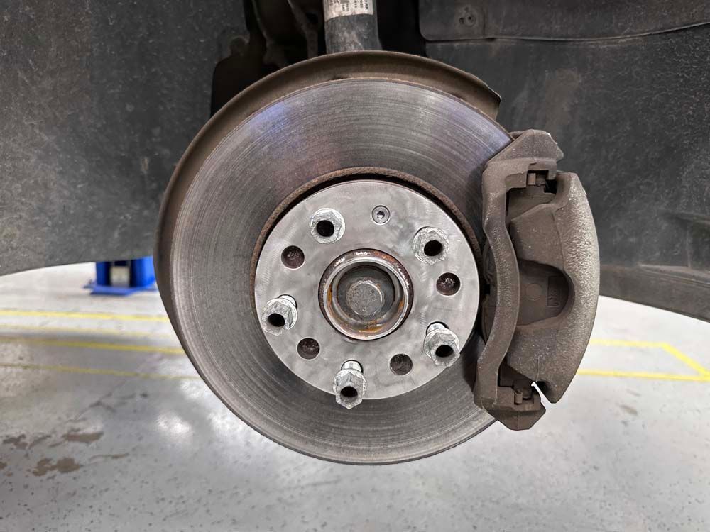 A close up of a brake disc on a car in a garage.
