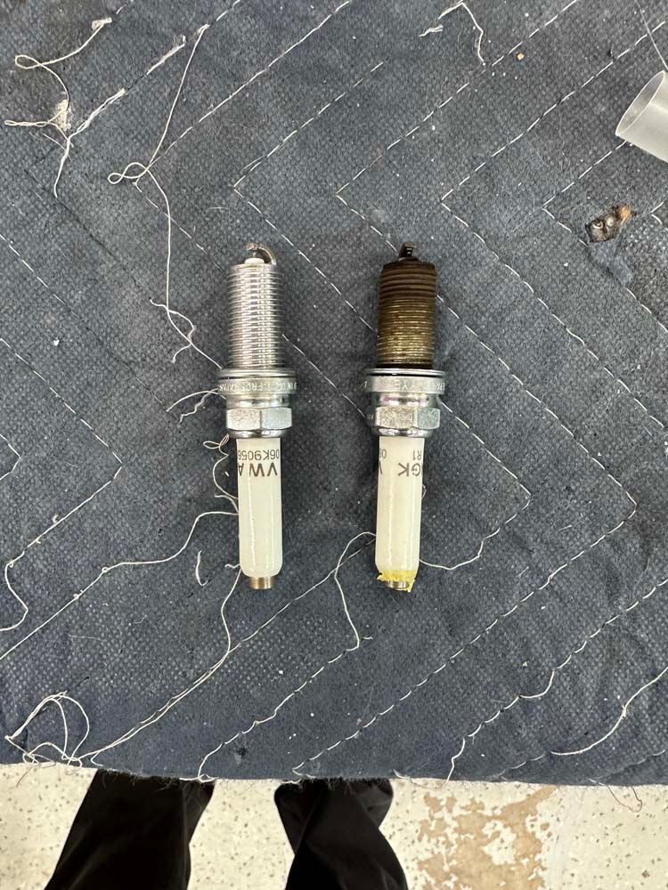 Two spark plugs are sitting next to each other on a table.