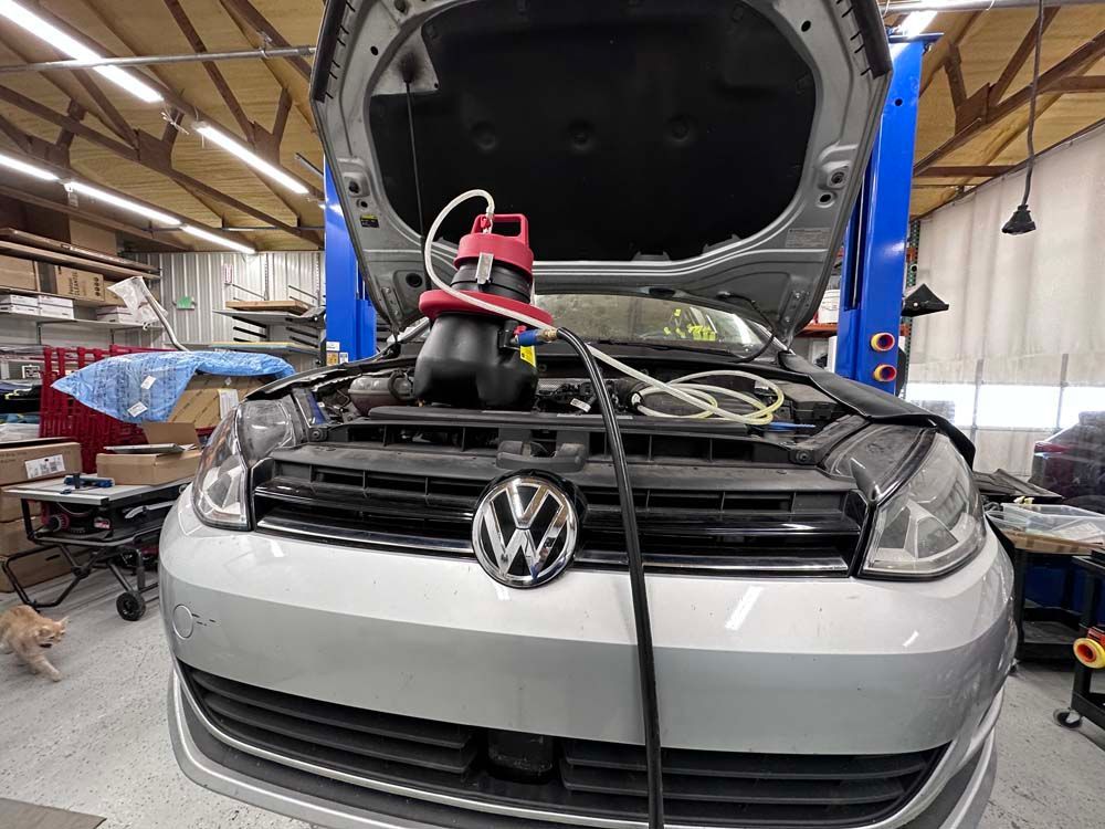 A volkswagen golf is being worked on in a garage with the hood open.
