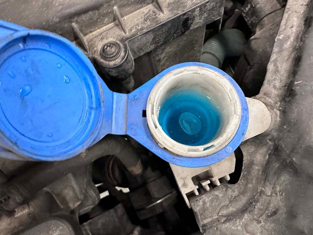 A close up of a bottle of blue liquid in a car.