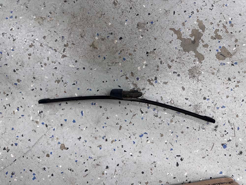 A wiper blade is laying on a concrete surface.