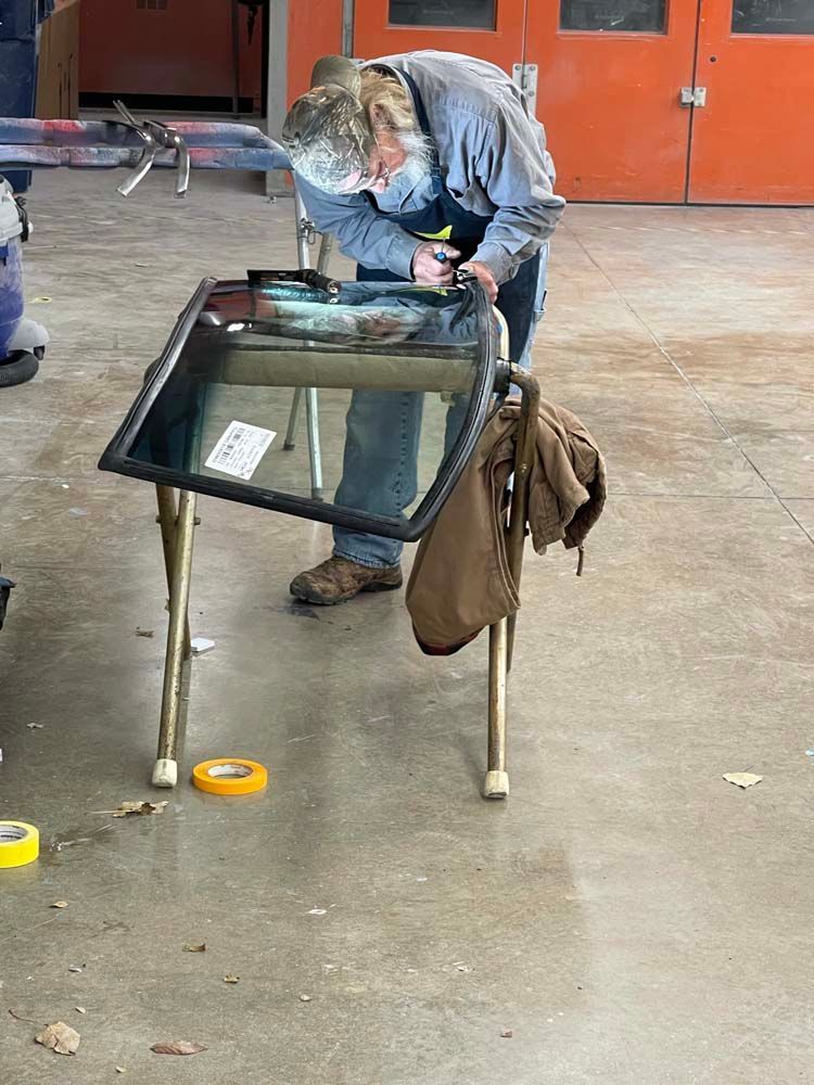 A man is welding a windshield in a garage.