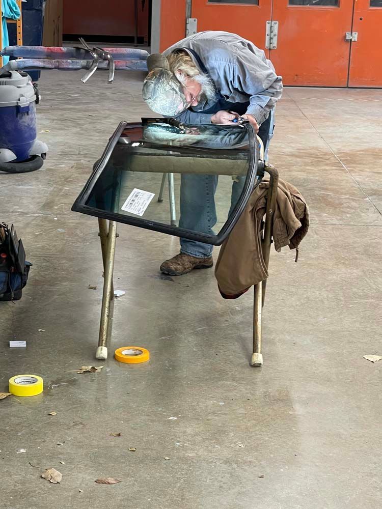 A man is working on a windshield in a garage.