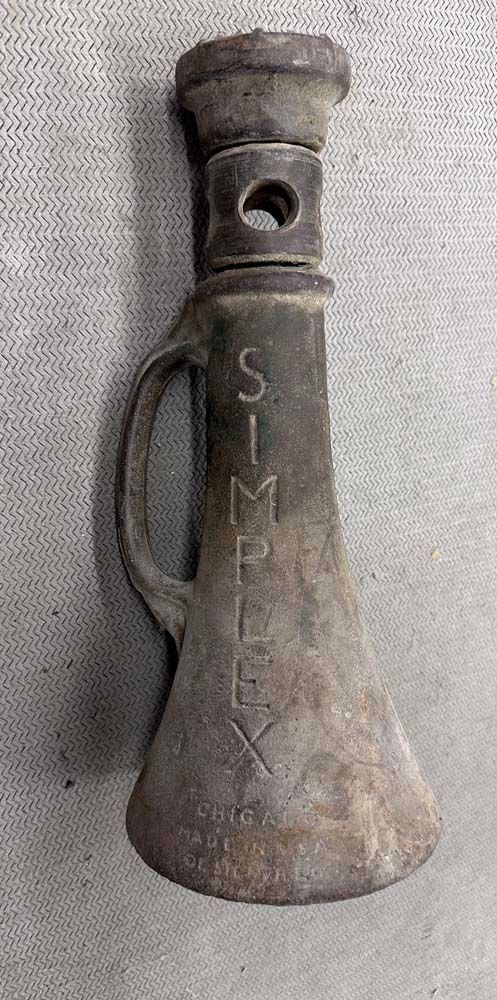 An old rusty jack with a handle is sitting on a table.