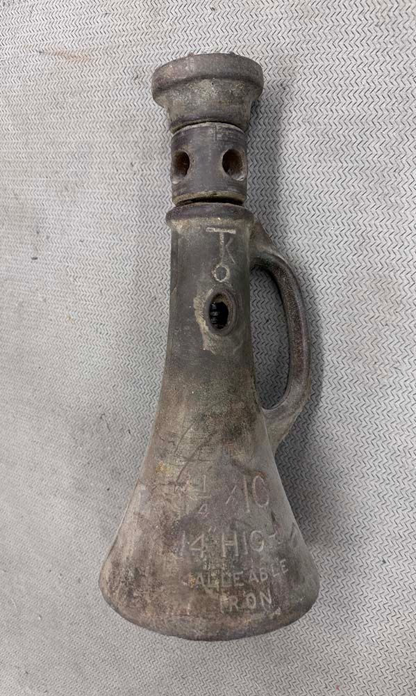 An old rusty jack with a handle is sitting on a gray surface.
