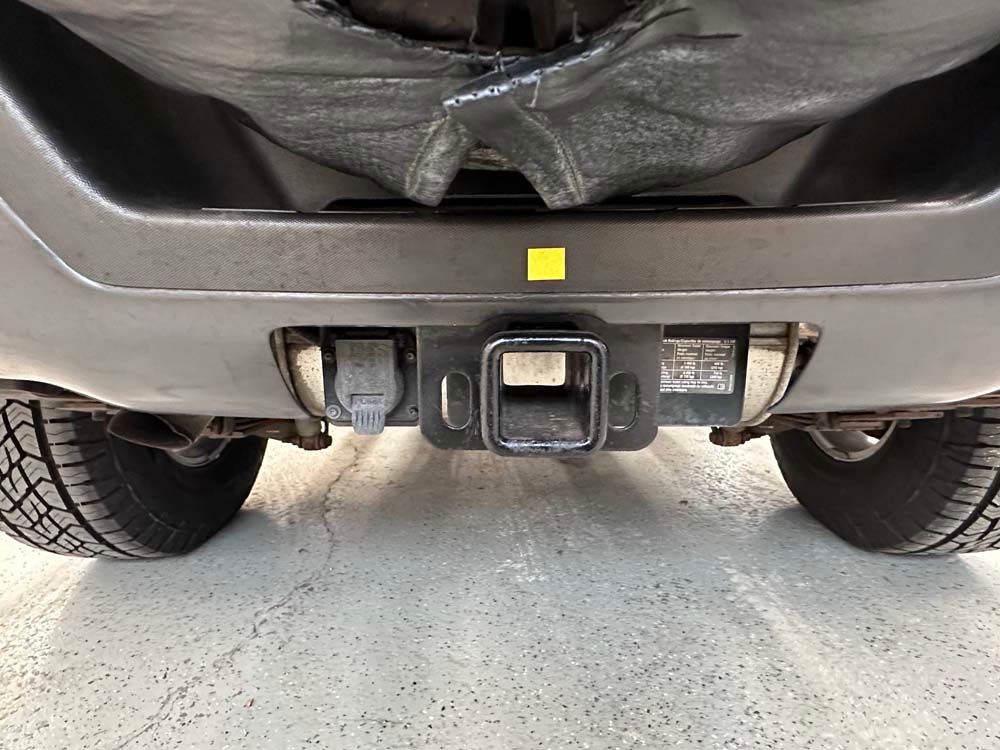A close up of the rear bumper of a car with a trailer hitch attached to it.