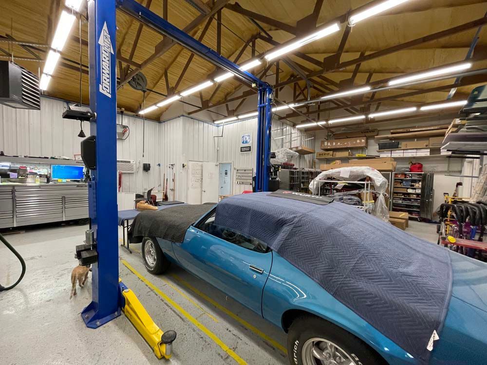 A blue car is parked on a lift in a garage.