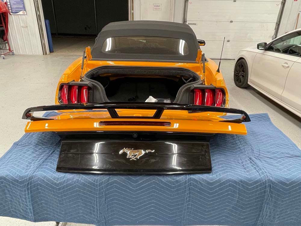 A mustang convertible is sitting on a blue blanket in a garage.