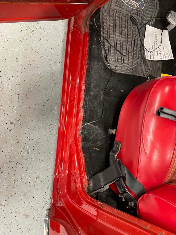 A red car is parked in a garage with the door open.