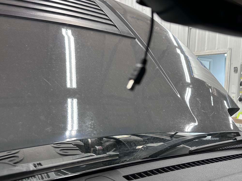 A close up of a car windshield with a cable hanging from it.
