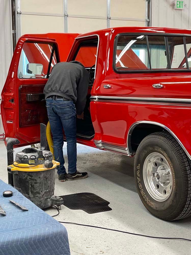 A man is working on a red truck in a garage.