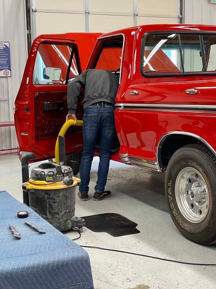 A man is working on a red truck in a garage.