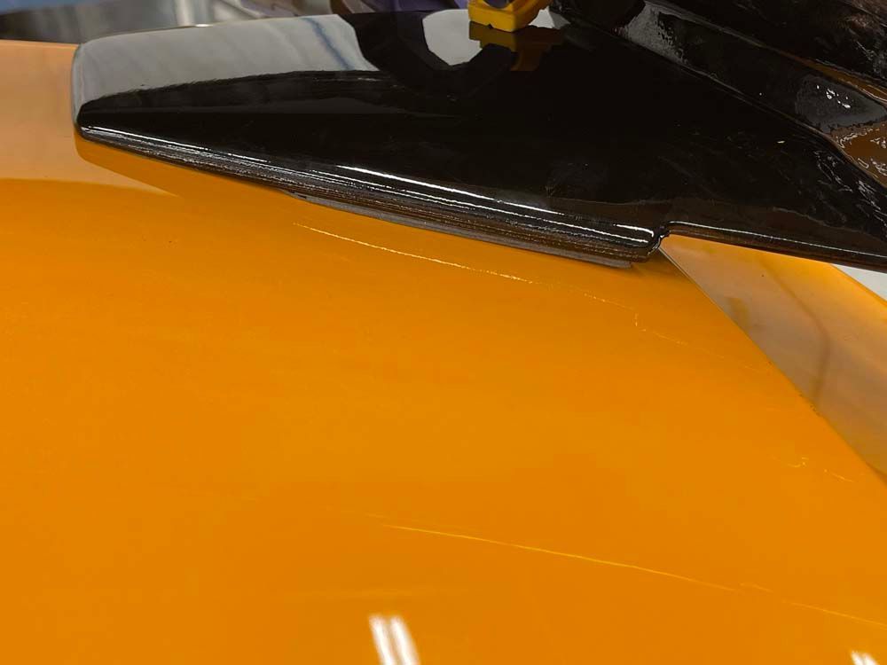 A close up of a yellow car with a black helmet on it
