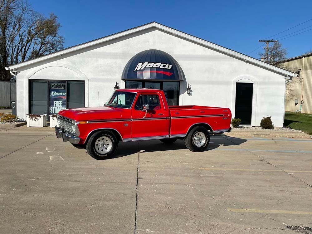 A red pickup truck is parked in front of a white building.