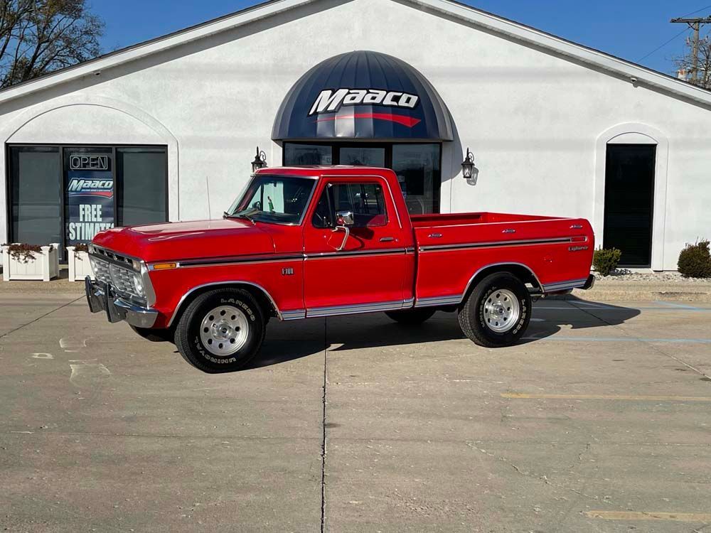 A red pickup truck is parked in front of a white building.