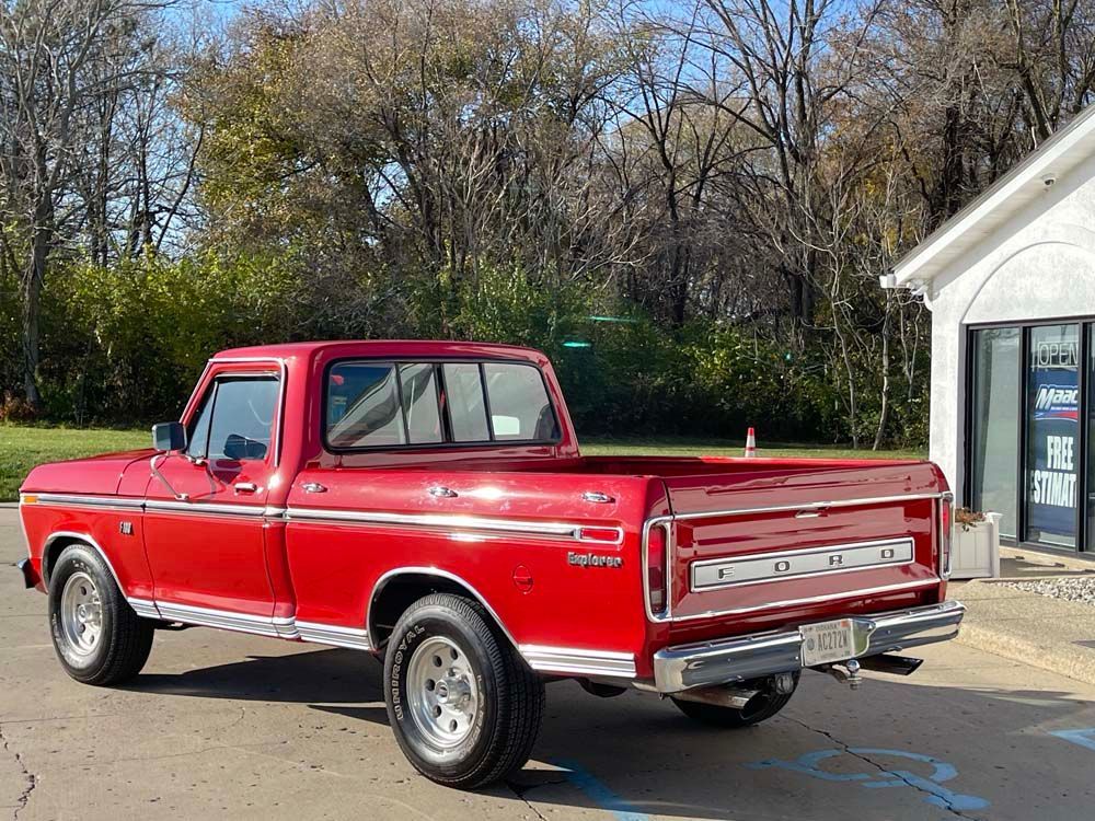 A red truck is parked in a parking lot in front of a building.