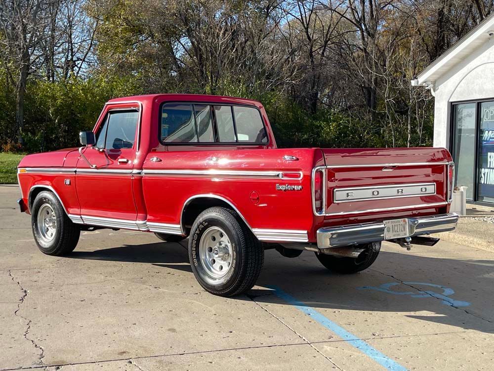 A red truck is parked in a parking lot in front of a building.