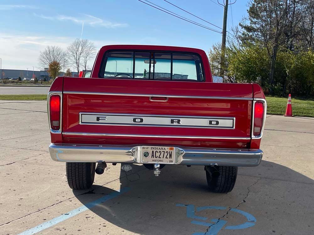 A red ford truck is parked in a handicapped parking spot.