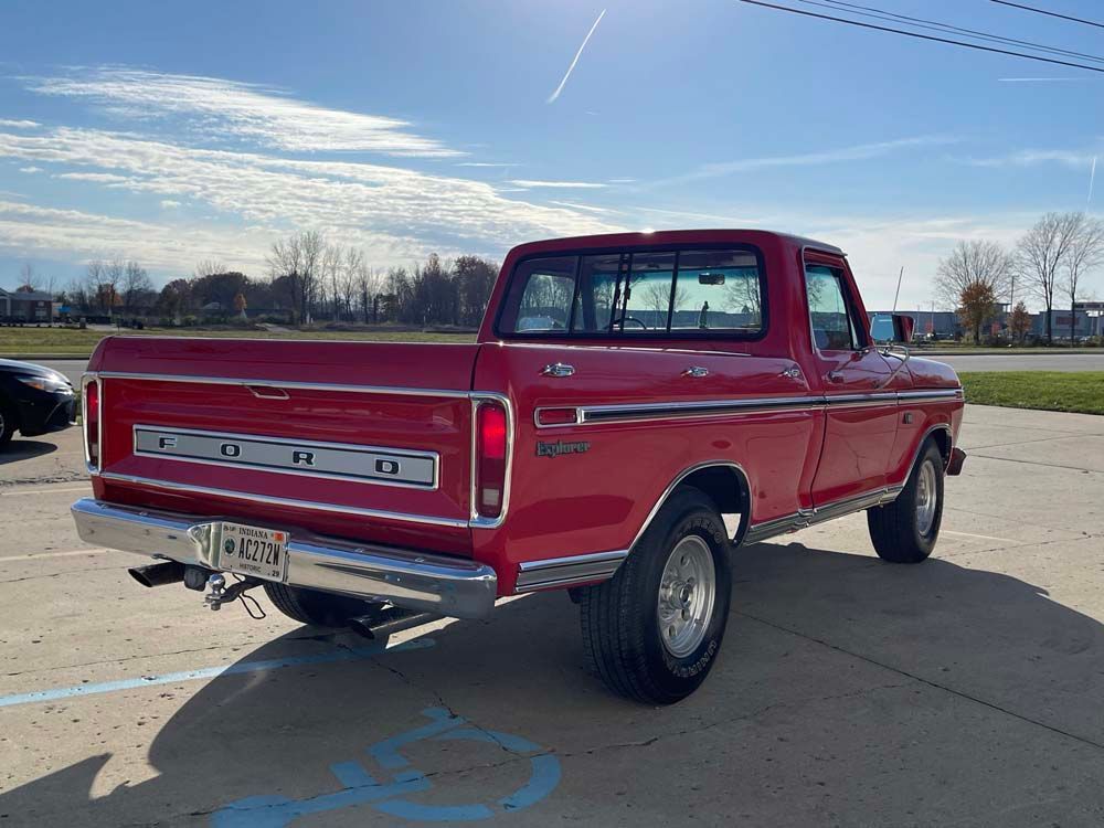 A red ford truck is parked in a handicapped parking spot.