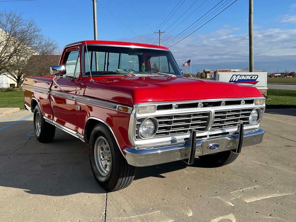 A red ford truck is parked in a parking lot.