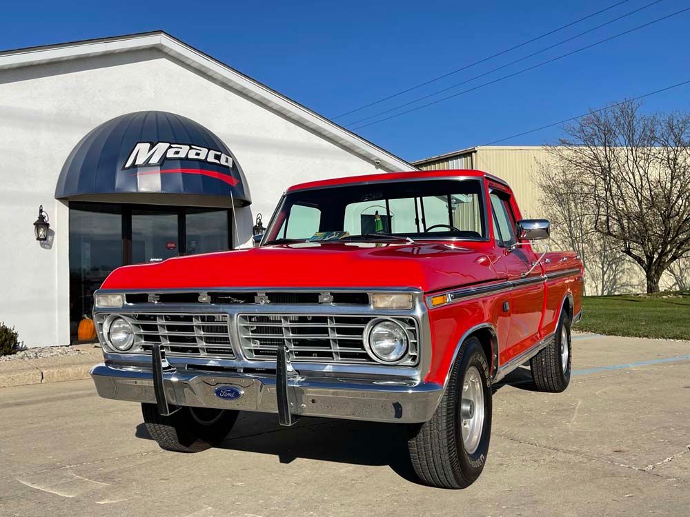 Red vintage Ford pickup truck parked in front of a building with the name 