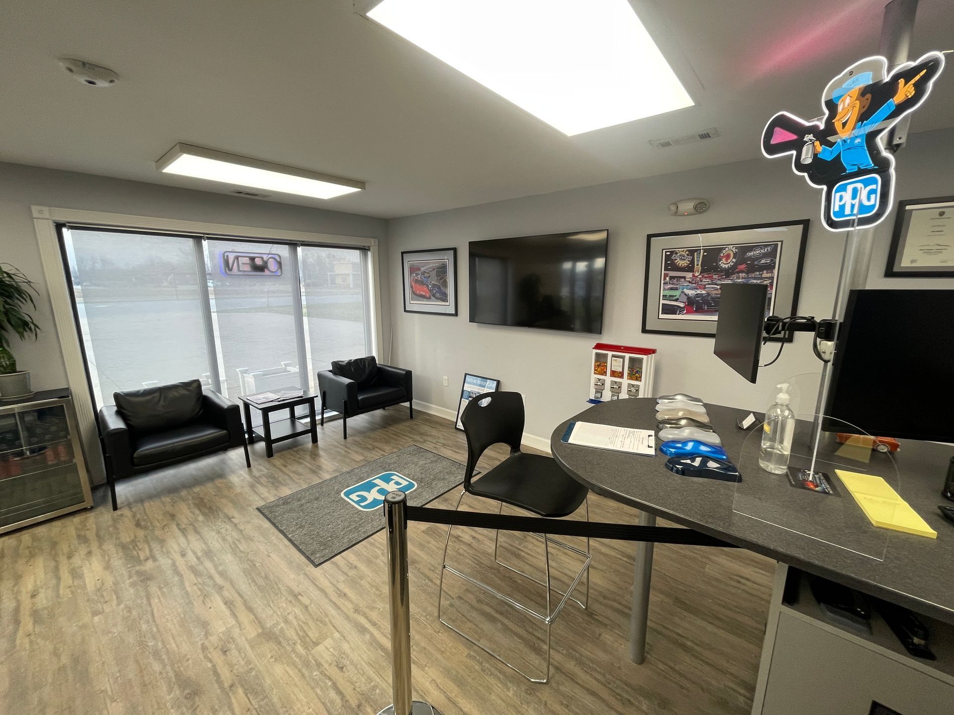 A waiting room with a desk , chairs , television , and a sticker on the wall.