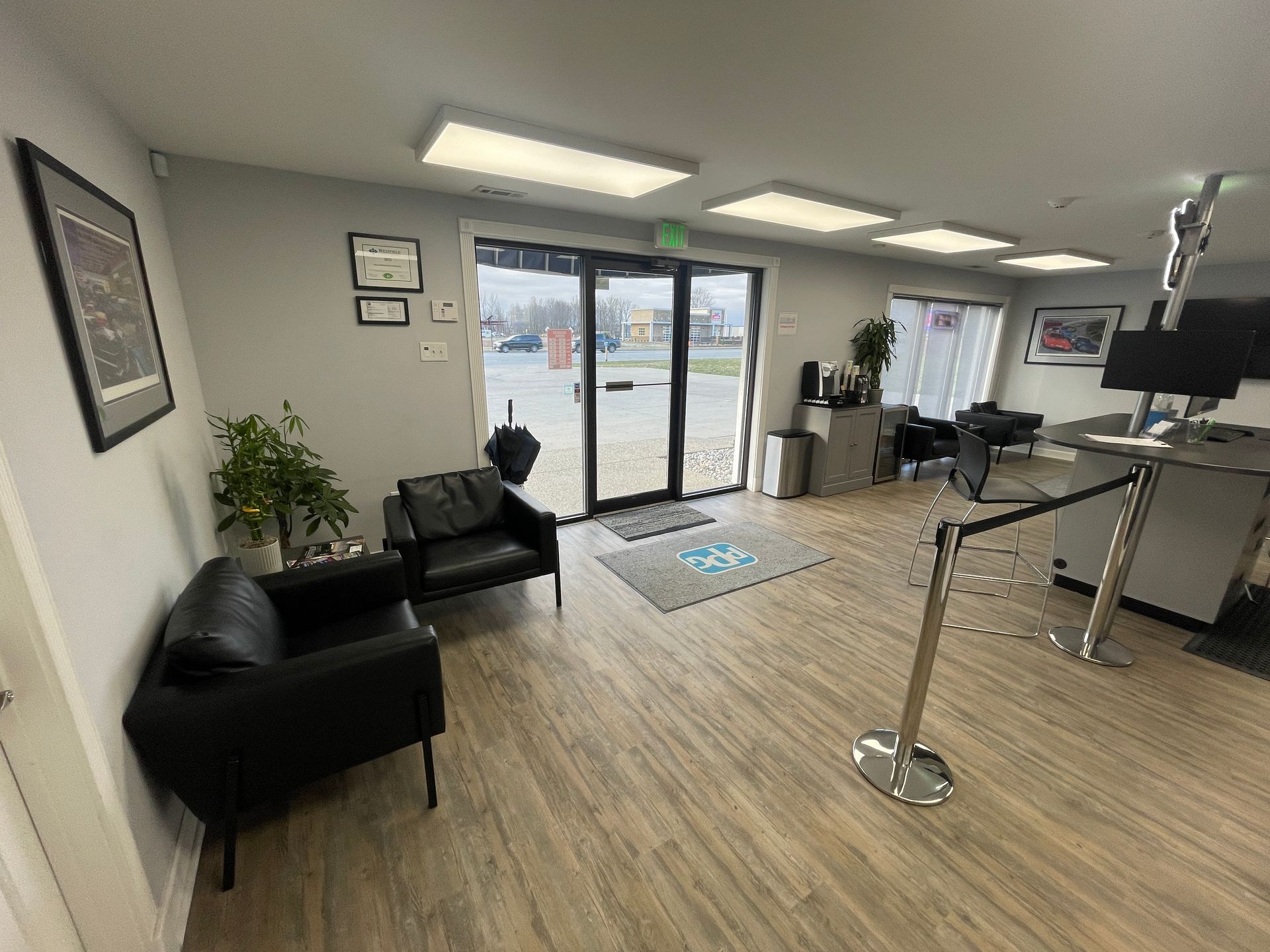 A waiting room with two black chairs and a bar.