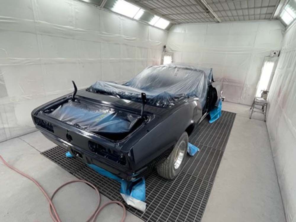 A car is being painted in a paint booth.