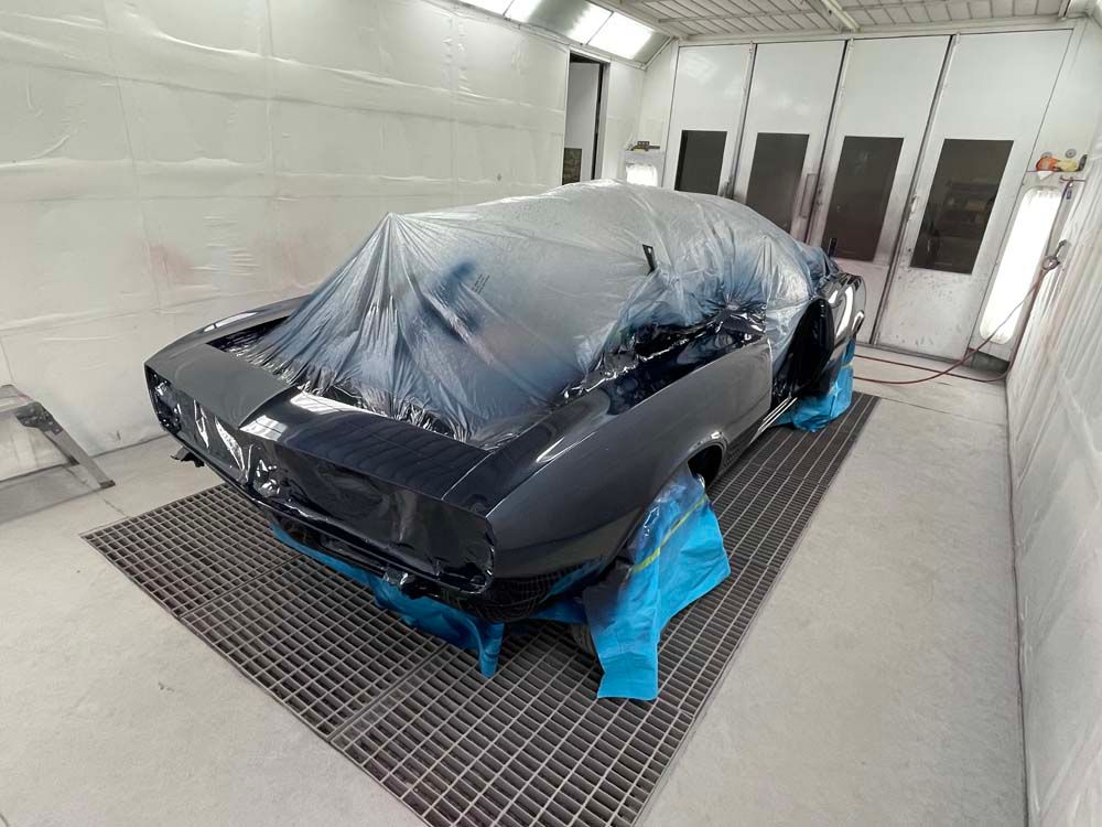 A car is being painted in a paint booth.