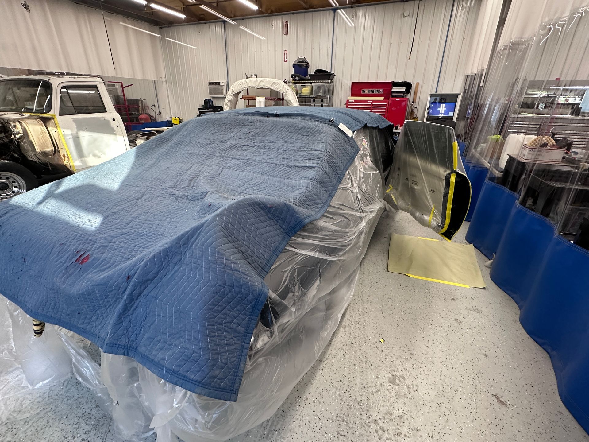 A car is wrapped in plastic in a garage.