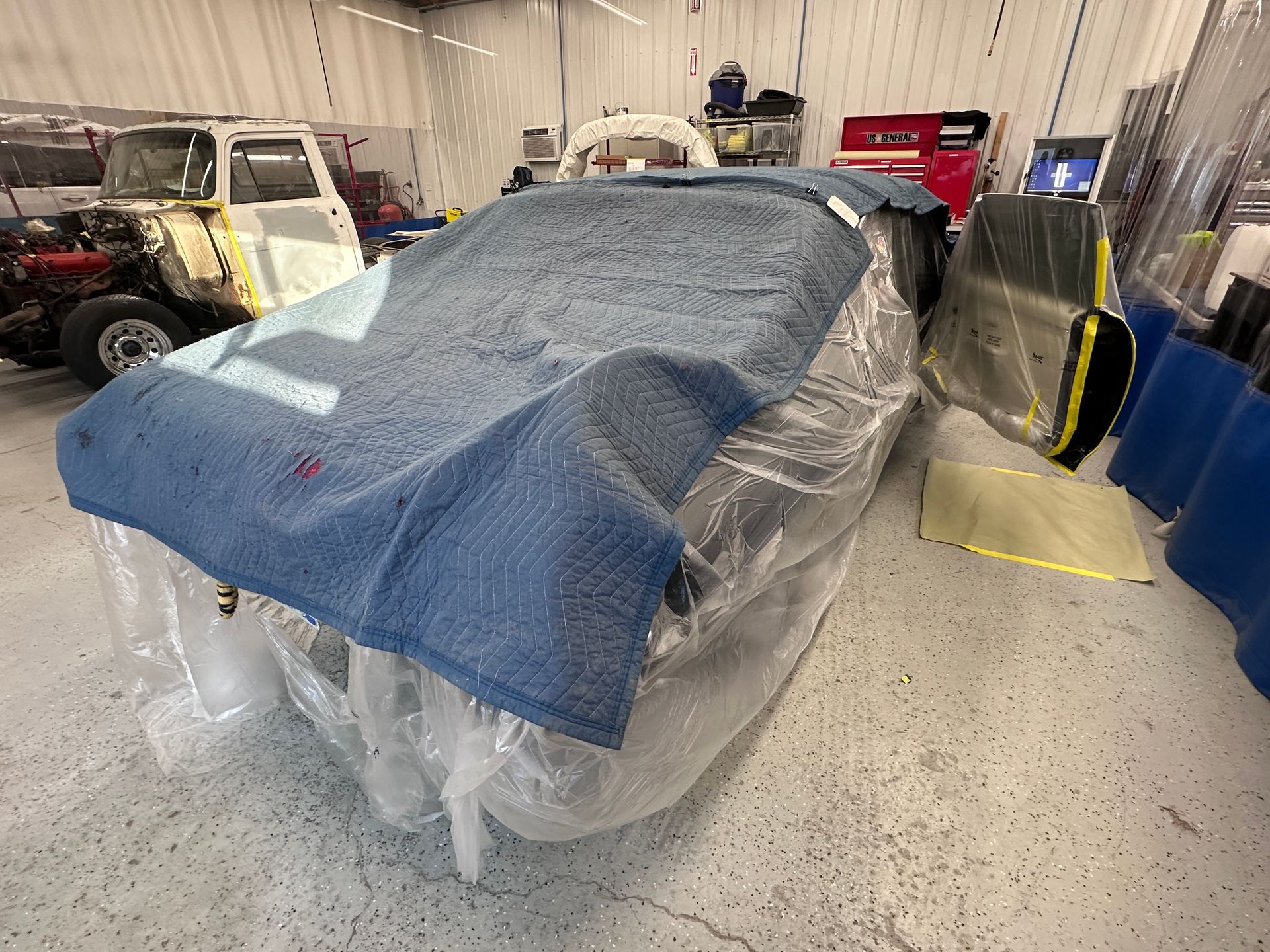 A car is wrapped in plastic in a garage.