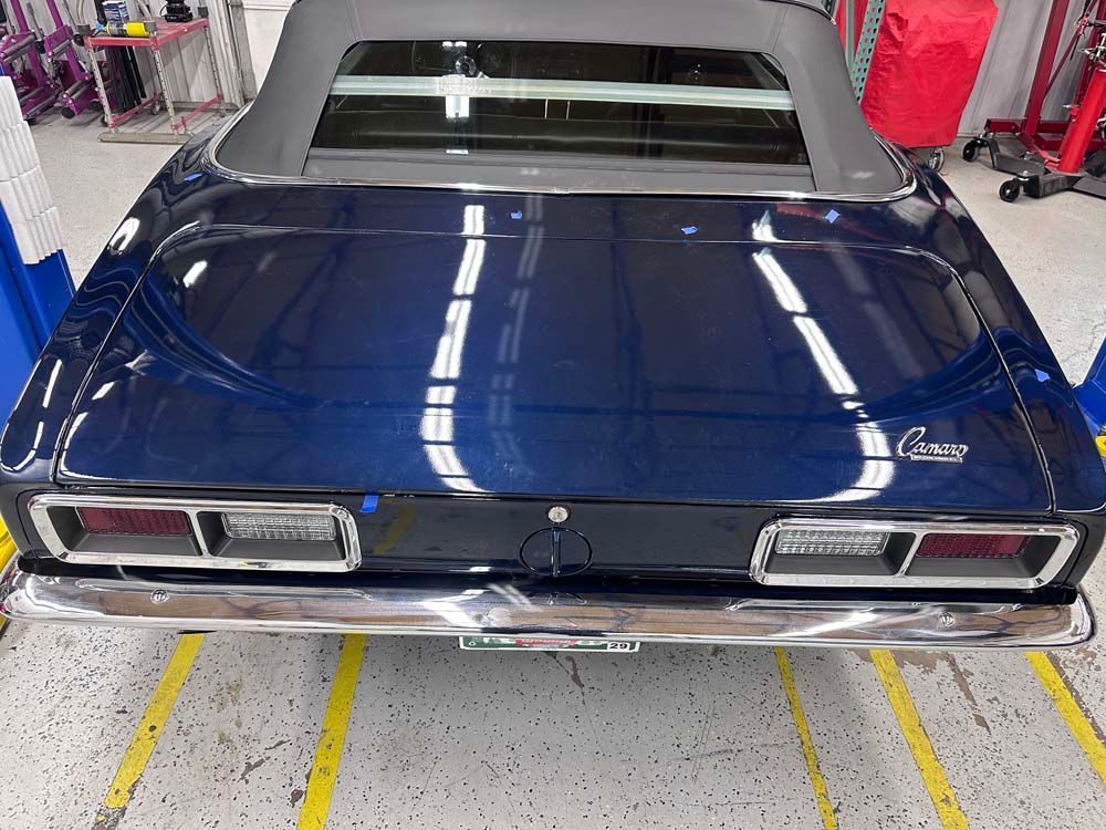 A blue car with a convertible top is parked in a garage.