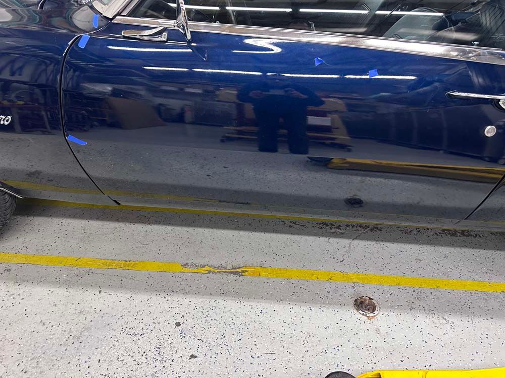 A blue car is parked in a garage next to a yellow line