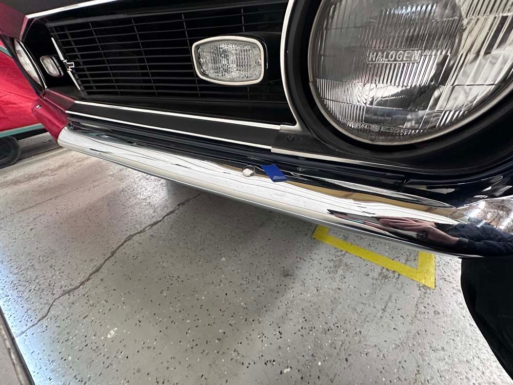 A close up of a car 's front bumper in a garage.